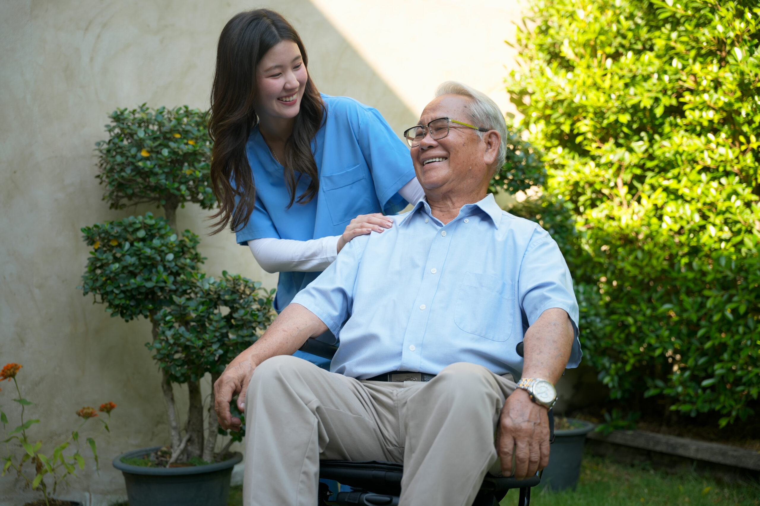 Caregiver assists elderly man outside in garden during sunny day Home health care provider in Hays, KS assisting a senior woman with daily living support at home.